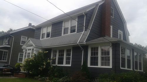 front facing picture of a house with new dark painted siding